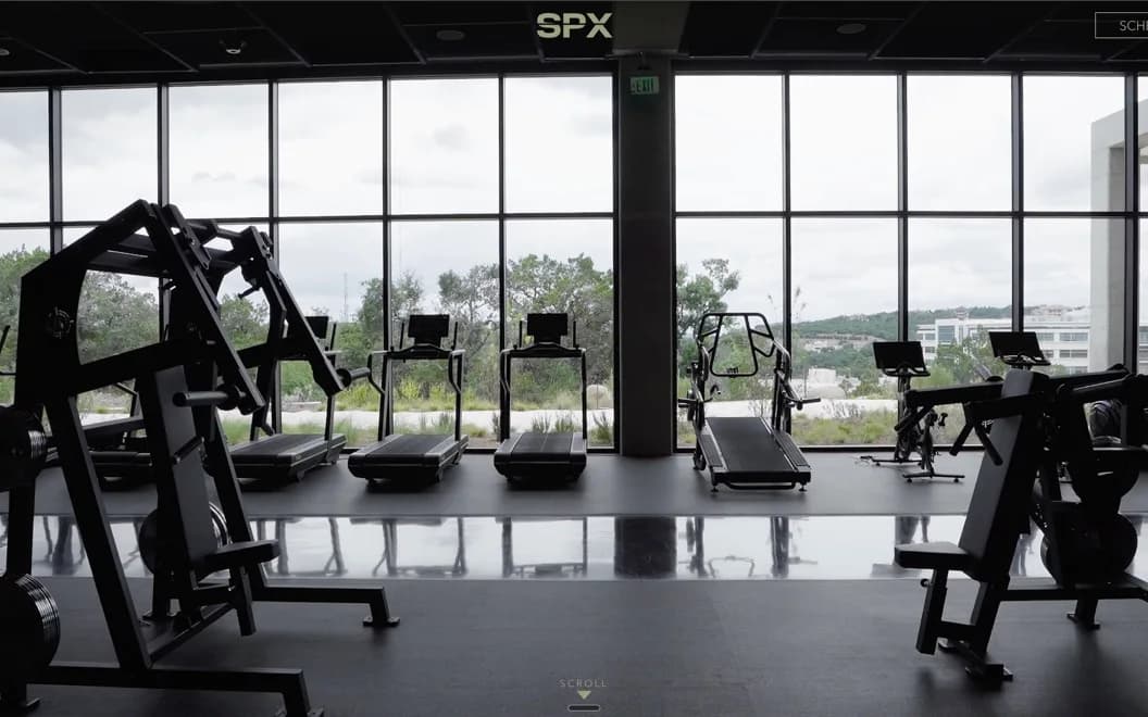 The SPX Gym Design homepage, a daylit gym floor of black weight machines and treadmills along a wall of full height windows.